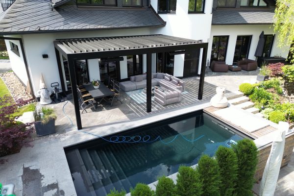 Lamellendach I Außenbereich Terrasse Hotel Resort Auf dem Bild sehen wir eine Außenterrasse in einem Luxus Resort/Hotel mit Pool und modernem Lamellendach von GastroDesign24.de