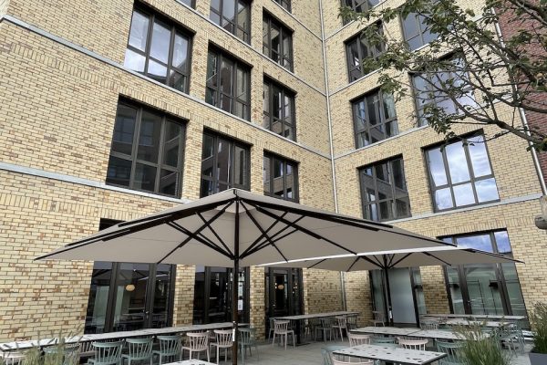 Profi Großschirm Big Ben von Caravita I Referenz Berlin Friedrichshain Außenbereich Außenbereich eines Gastronomiebetriebs in Berlin mit mehreren wetterfesten Gastro-Sonnenschirmen. Die Schirme sind für wechselnde Witterung ausgelegt und strukturieren den Sitzbereich klar.